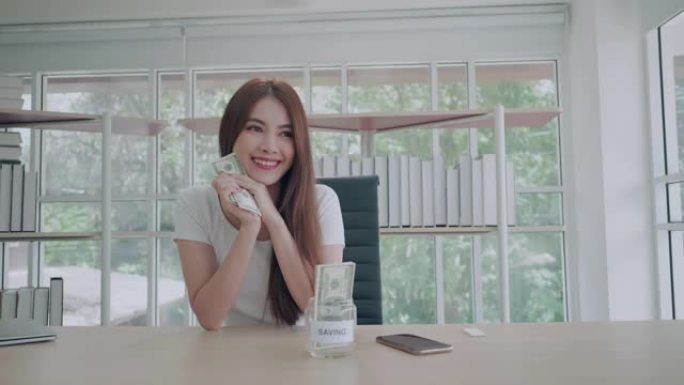 美丽的亚洲年轻女子数钱存钱。