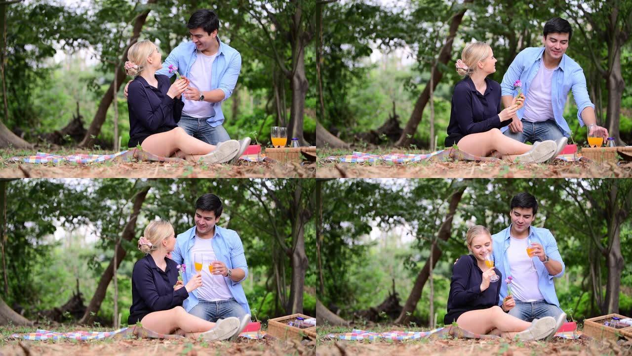 坐在野餐时，男友在公园送礼物使女友感到惊讶。