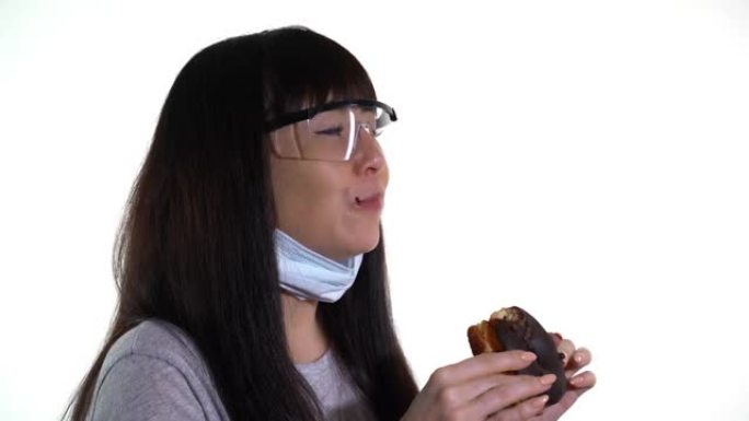 戴着医用口罩和护目镜的女人吃甜甜圈