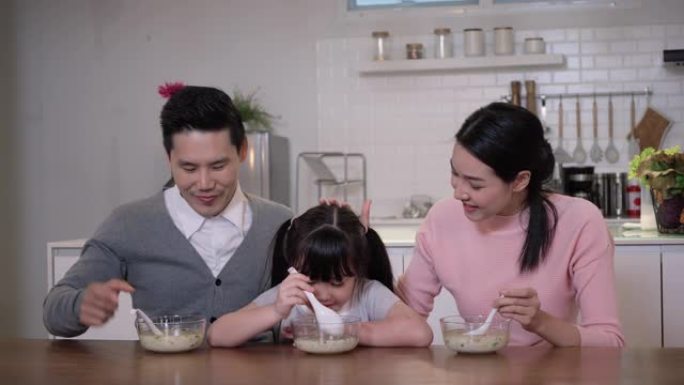 周年快乐亚洲家庭一起坐在家里的厨房里吃便餐。父亲和母亲与儿子和女儿一起吃饭。家庭和医疗的概念。