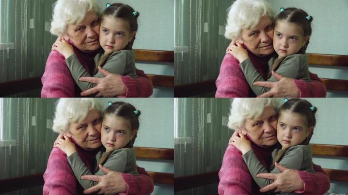 深情快乐的成年老奶奶和可爱的可爱悲伤的小孩孙女看着相机。两代人之间的温暖关系