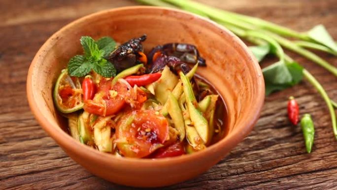 Som Tam是受欢迎的泰国菜。芒果沙拉配干虾、咸蟹、辣椒、番茄和辛辣香草。配蔬菜。静静在工作室拍摄