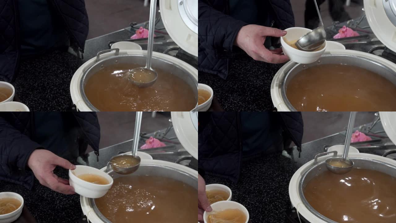 一个穿着黑色毛衣的年轻人在早餐时在客运渡轮上用勺子拿起味噌汤