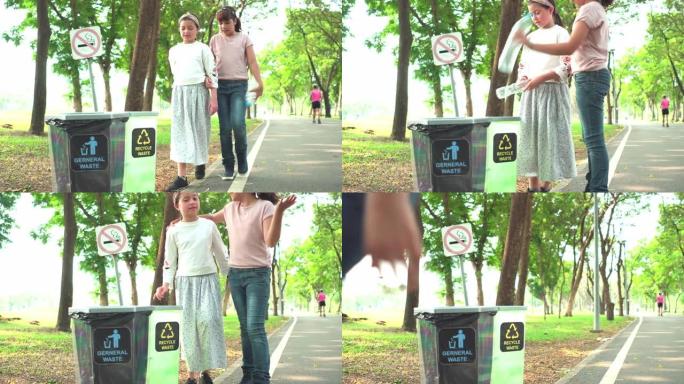 在周末的晴天，高加索人和亚洲可爱的少女与朋友之间的混合种族在公园的回收站中扔透明的塑料瓶作为回收废物