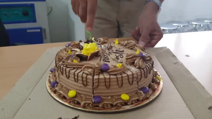 用刀将圆形巧克力生日蛋糕切成薄片。