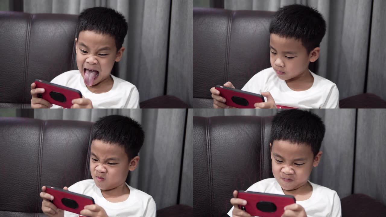 可爱的男孩玩智能手机游戏。