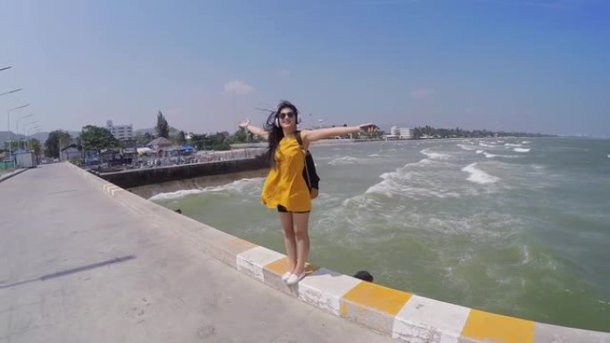快乐的亚洲女人，用耳机在阳光明媚的日子走在华欣码头，生活方式的概念。