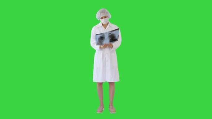戴着面具的女医生在绿色屏幕上看着肺部x射线，色度键
