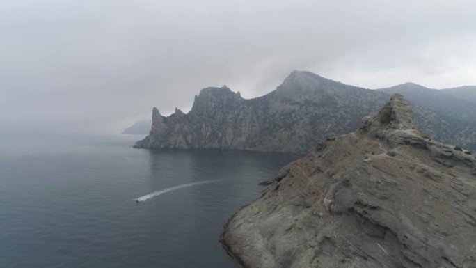 空中。飞越海中的岩石和漂浮的船。多云天气