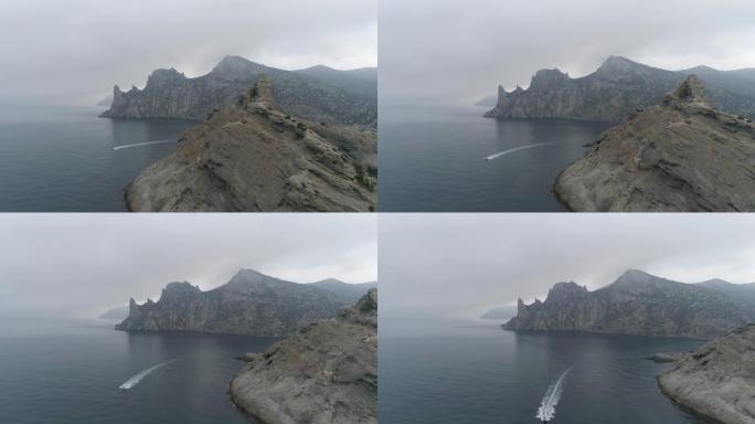 空中。飞越海中的岩石和漂浮的船。多云天气