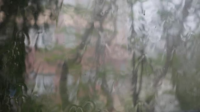 强烈的雨水冲向窗户玻璃并流下来。特写。雨季玻璃背景上的雨滴。4k