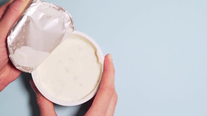 新鲜的有机酸奶，提供适当的营养。女性双手慢慢打开酸奶的盖子，隔离在白色背景4k