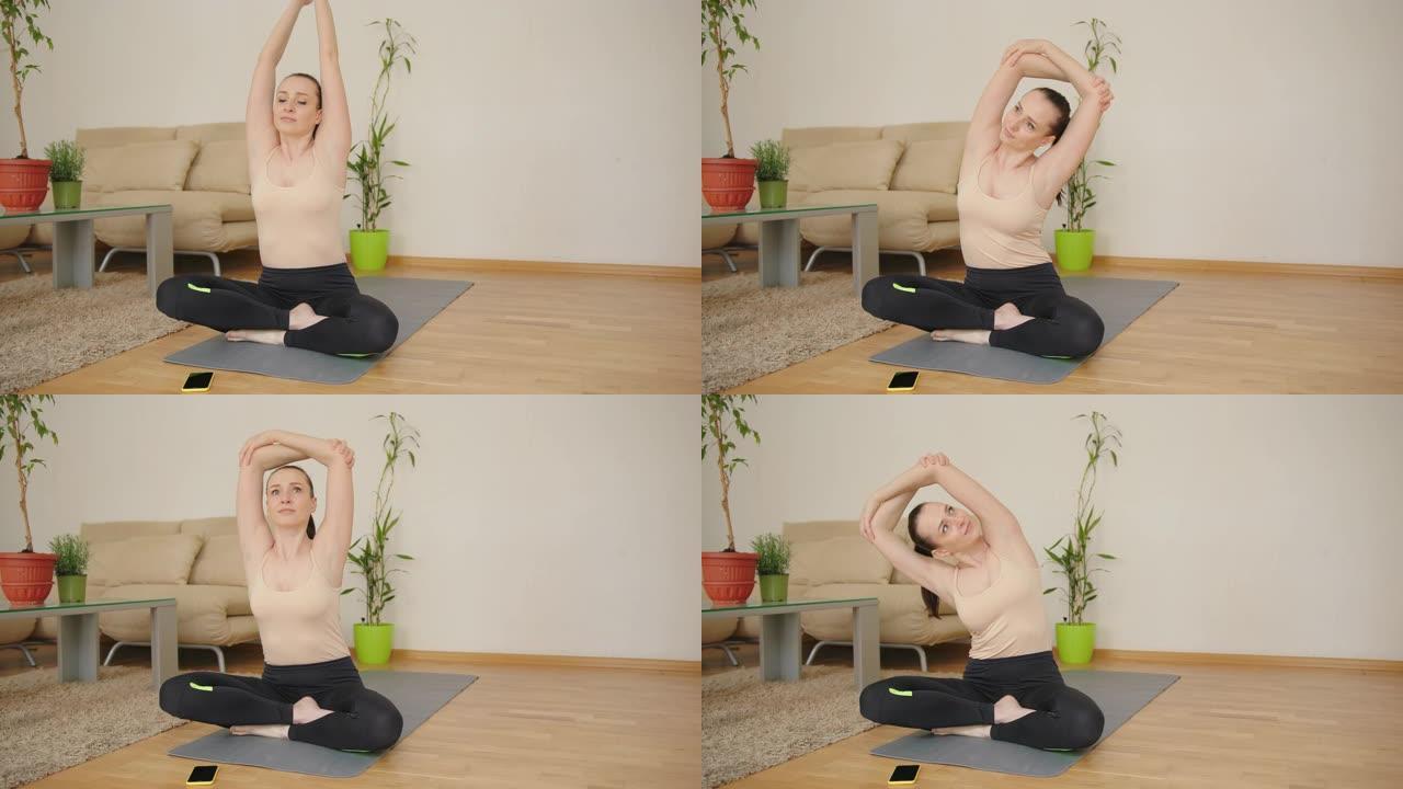 集中的女人在家中在瑜伽健身垫上做伸展晨练运动，以莲花体式姿势