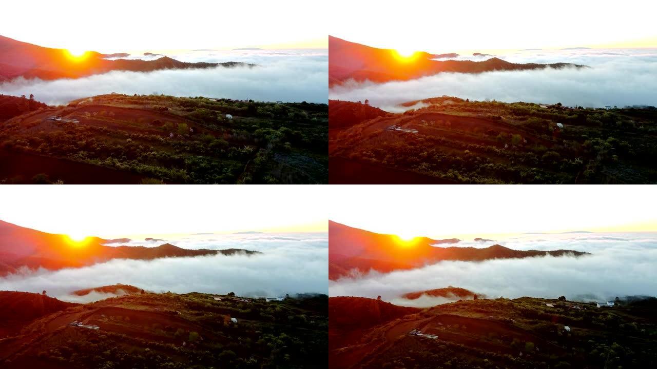 山谷中的云层很低，随着太阳的升起，它创造了一个美丽的形象，太阳冲破了云层，在山丘后面。黄昏