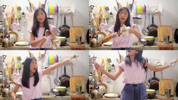 快乐的亚洲女孩在厨房洗碗，在家跳舞。