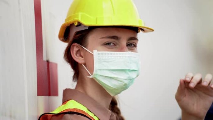 劳动女工下班后坐在室外仓库工厂放松。行业工人佩戴防护面罩面部和安全帽的概念。