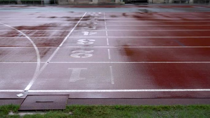 雨天在体育场跑步。侧面射击。轨道上有数字。