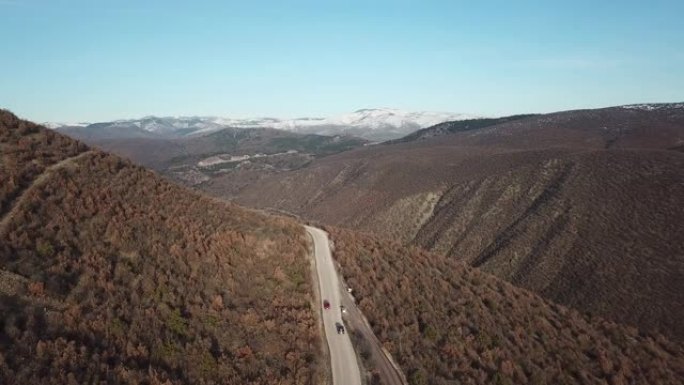 秋季景观中的汽车在山林路上行驶。旅行和旅程概念无人机视频。