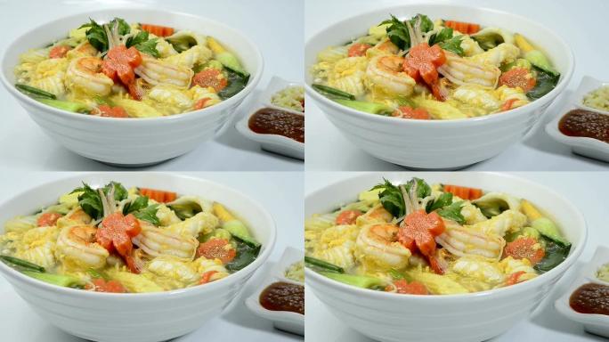 泰国寿喜烧汤配海鲜虾、鱿鱼、鸡蛋和蔬菜雕刻胡萝卜花朵造型酱汁