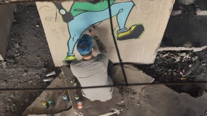 一位年轻的艺术家在一个废弃的房子里用有趣的几何图形画涂鸦。气溶胶涂料。从上面看。