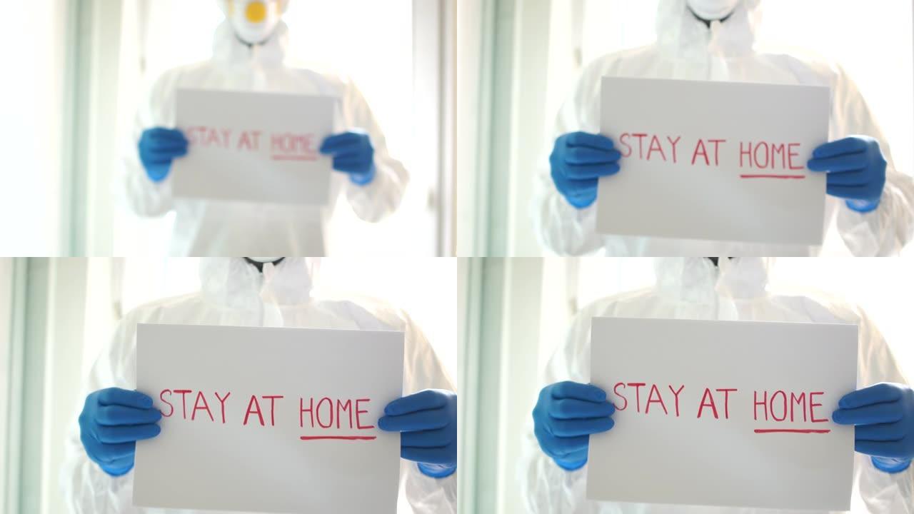 美国的新冠肺炎疫情。一个穿着防护服的男人举着写着“待在家里”的牌子的特写
