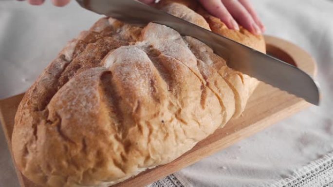 家庭主妇用长刀在木板上切成面包