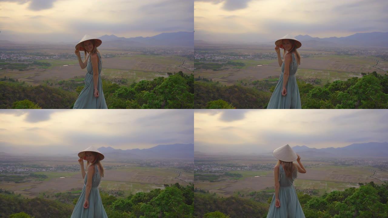 一位年轻的游客站在山顶上，可以欣赏山谷的壮丽景色。她戴着一顶亚洲帽子