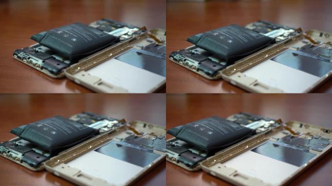 膨胀的智能手机电池。电池故障的智能手机损坏。木制背景上损坏的手机。