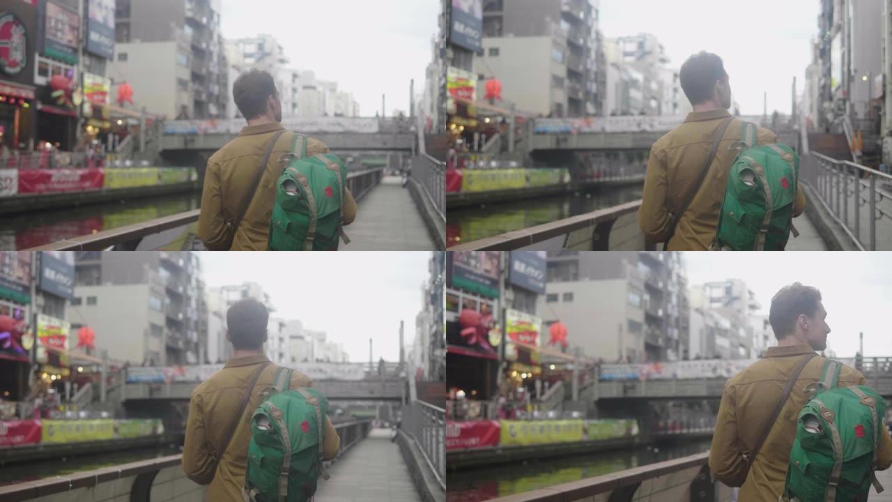 成年男子走在大阪道顿堀的通博里运河旁