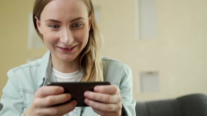 开朗快乐，微笑的年轻女子玩智能手机游戏，水平拿着手机作为通过比赛关卡，汽车游戏