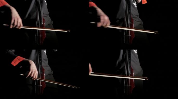 一个男人的手在黑色背景上演奏电动大提琴，弦乐，弓和指板的特写镜头，孤立