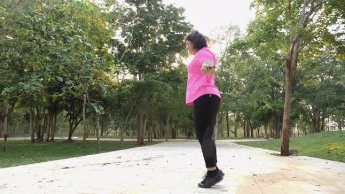亚洲高加索胖女孩漂亮的脸穿着粉红色的运动服，早上在公园跳绳运动，保健运动减肥