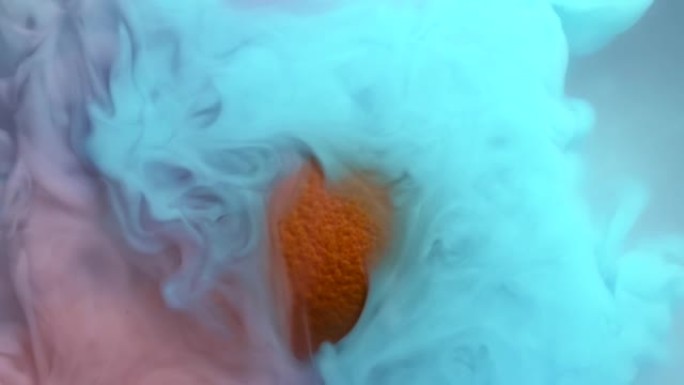 在水中混合蓝色和粉红色油漆的慢动作，在浑浊液体中向橙色水果飞溅和挥动，作为抽象流体水下背景