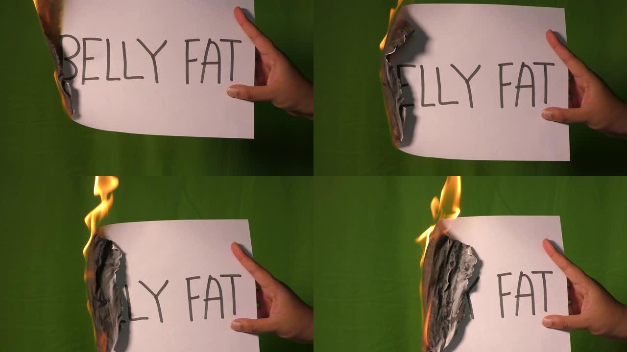 一只手握着上面写有腹部脂肪字的燃烧纸。