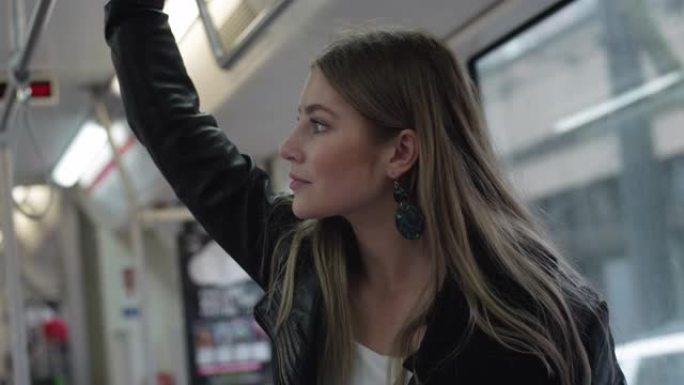 一位美丽的年轻女子在城市乘坐公共交通工具时抓着轨道
