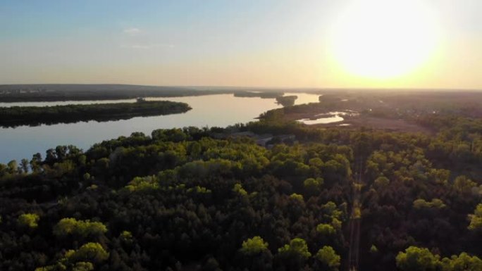 日落时，无人机在森林和河流上方进行空中勘测。