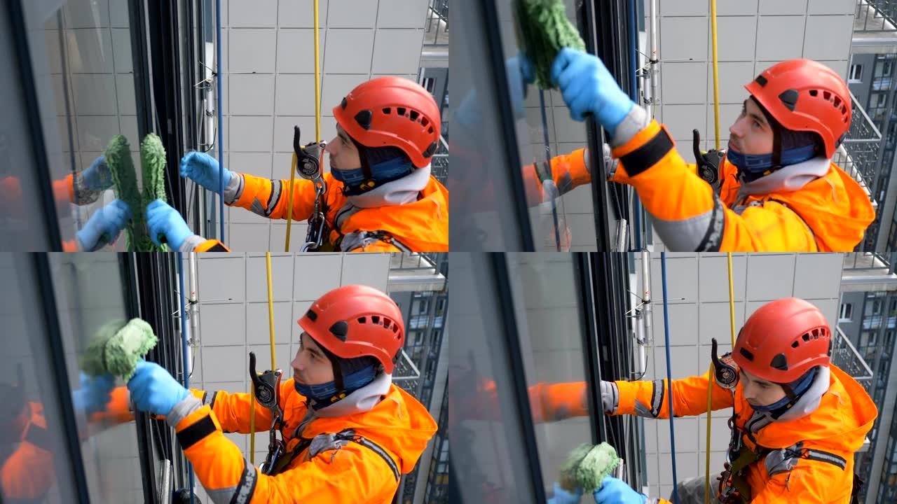 装备齐全的工业登山者在高层建筑中用皮大衣清洗窗户，慢动作