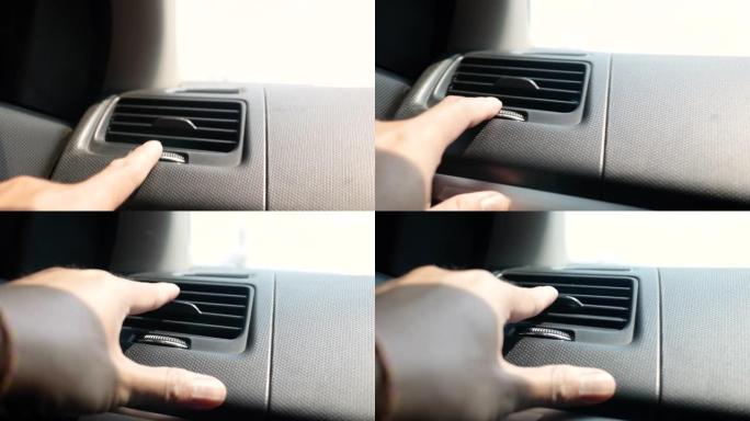 乘客手调节空气通风格栅或调节车内空调按钮的特写。