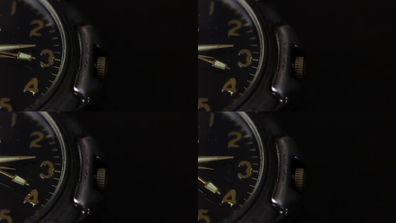 桌子上有一只手表。表盘的一部分是可见的。秒针移动。拍摄特写，在黑色背景上。