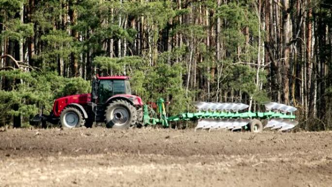 拖拉机上的农民转动犁，将金属刀片降入在阳光下闪闪发光的地面，春季耕作，农业综合企业