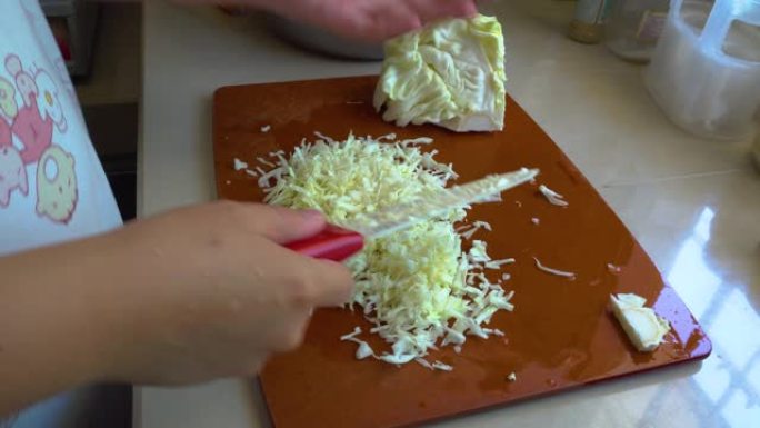 当地生活方式家庭主妇在砧板上切蔬菜卷心菜做沙拉。