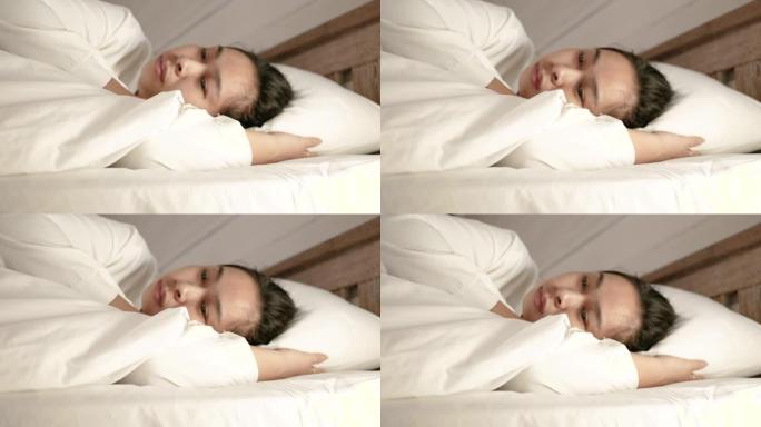 假期里，疲惫的亚洲妇女躺在床上，身上盖着白色毯子。