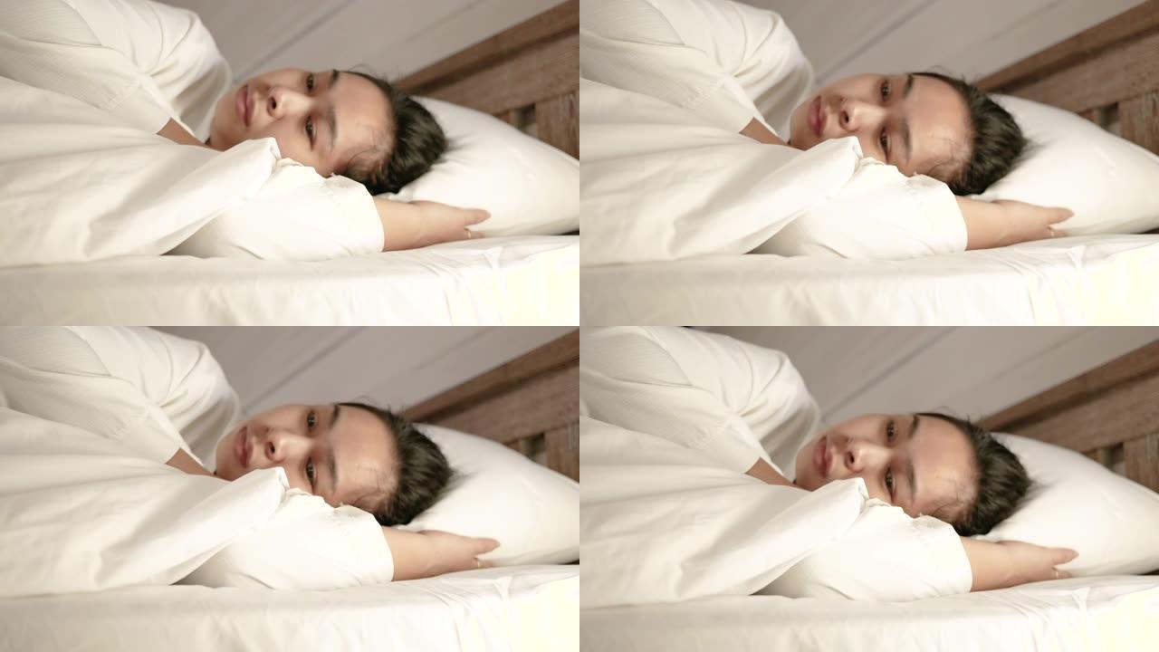 假期里，疲惫的亚洲妇女躺在床上，身上盖着白色毯子。