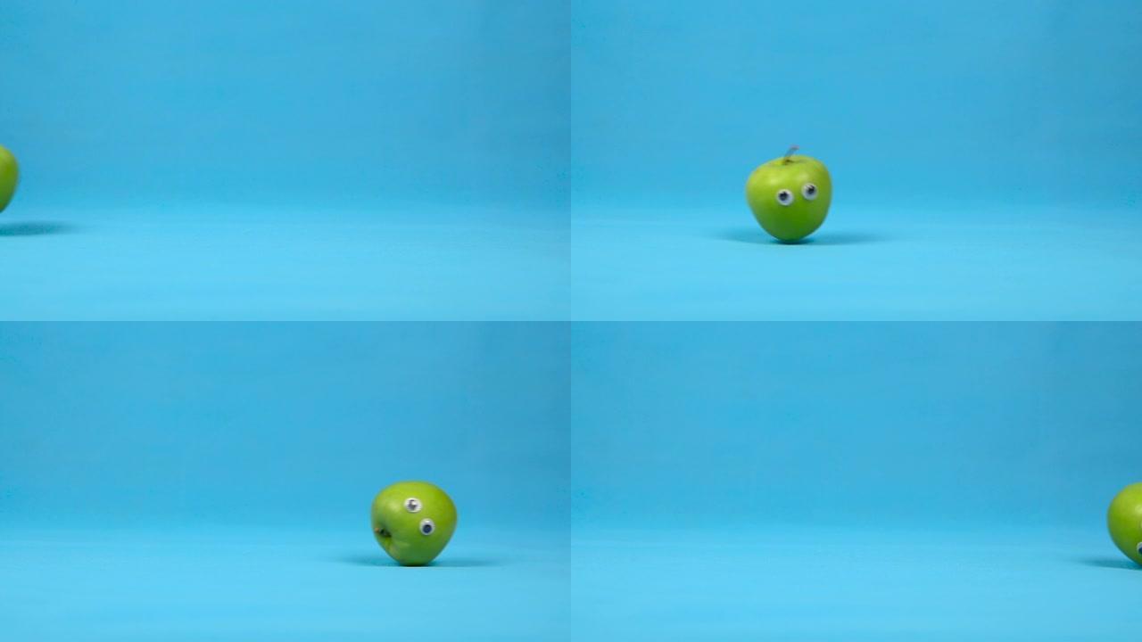 眼睛慢慢滚动的青苹果。蓝色背景上有卷的苹果。慢动作。