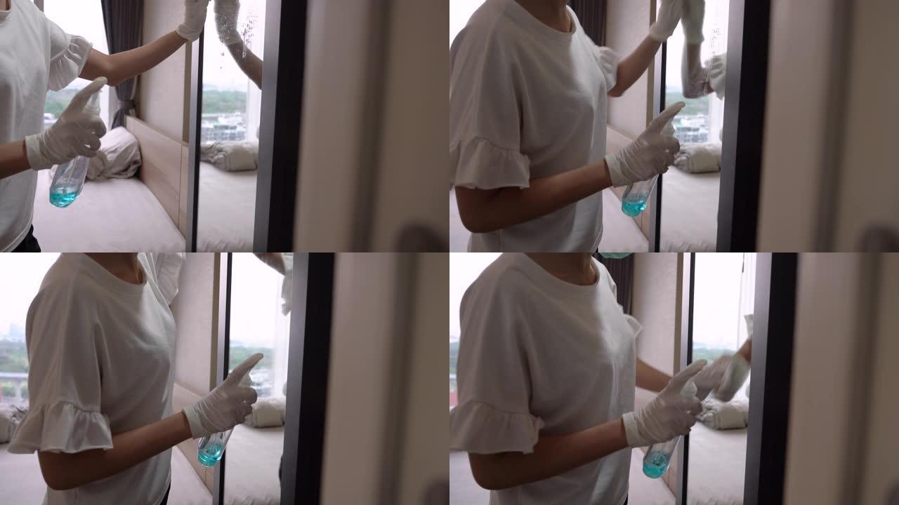 年轻的亚洲女性白手套通过喷雾和擦拭来消毒她的镜子，消毒家用家具，卫生保健，消毒剂擦拭，日间窗灯，电晕