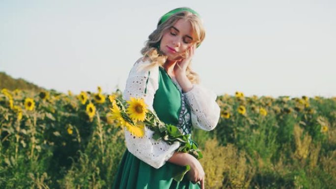 年轻美丽的斯拉夫女人享受美丽的自然向日葵田。手里拿着黄色的花。民族传统服装。绿色太阳裙白色衬衫。奢华