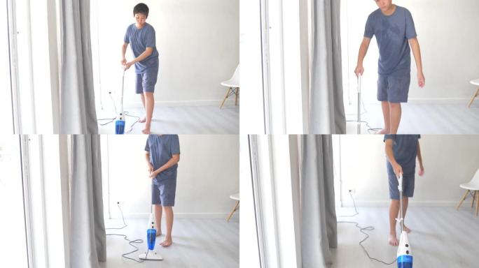 亚洲青春期男孩在家使用电动清洁吸尘器。
