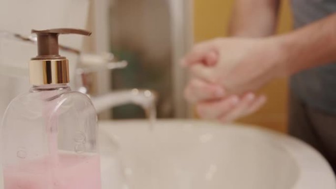 电晕病毒预防男子展示手卫生用热水肥皂洗手。使用皂液分配器模糊的手
