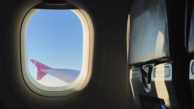 透过飞机窗户看飞机机翼在晚上。专注于窗框