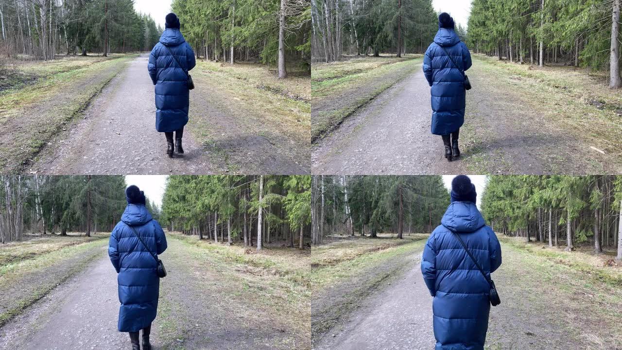 女人在小径上走过松树林高高的松树之间的空小路